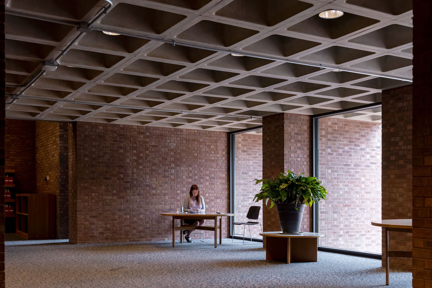 Interior shot of woman sitting at desk in a brick room in Columbus, Indiana's Cleo Rogers Memorial County Library