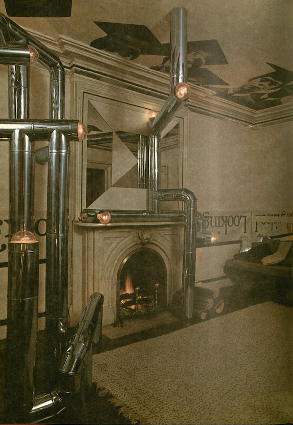 Vintage image of architect Hugh Hardy’s abstract New York apartment, featuring exposed silver pipes and a mantelpiece with a geometric mirror above it.