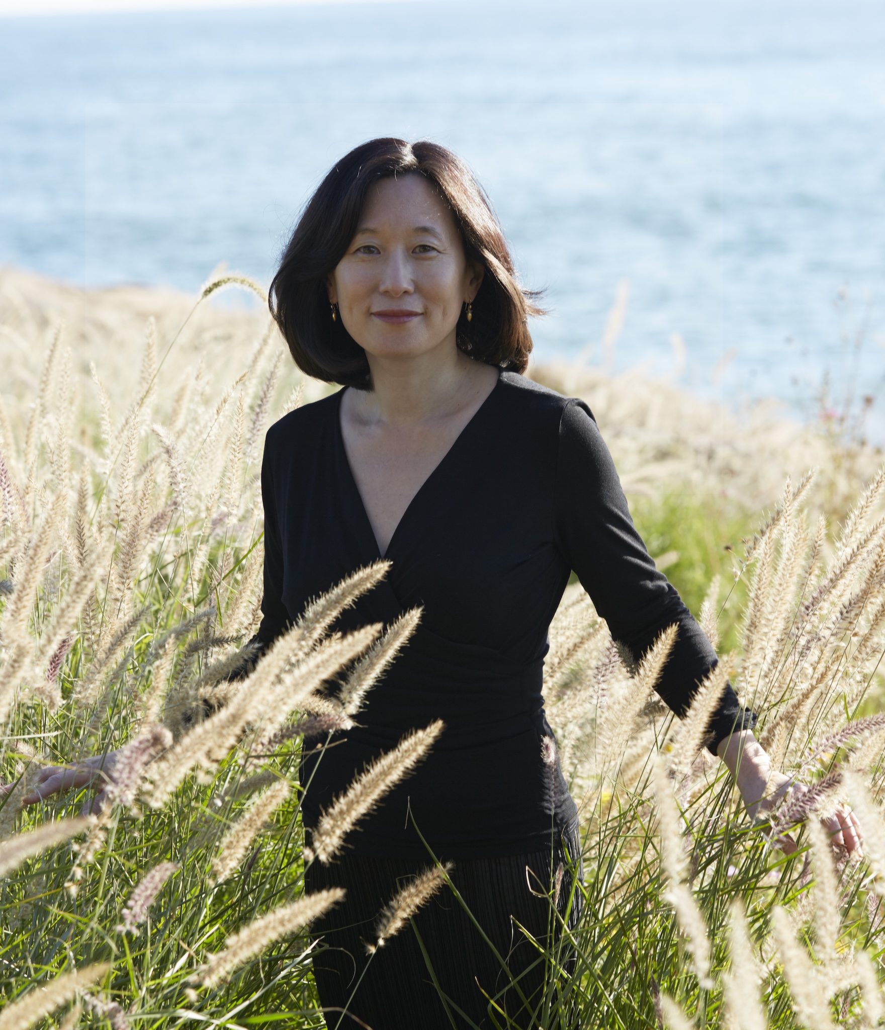 Portrait of architect Mikyoung Kim in a field by the ocean