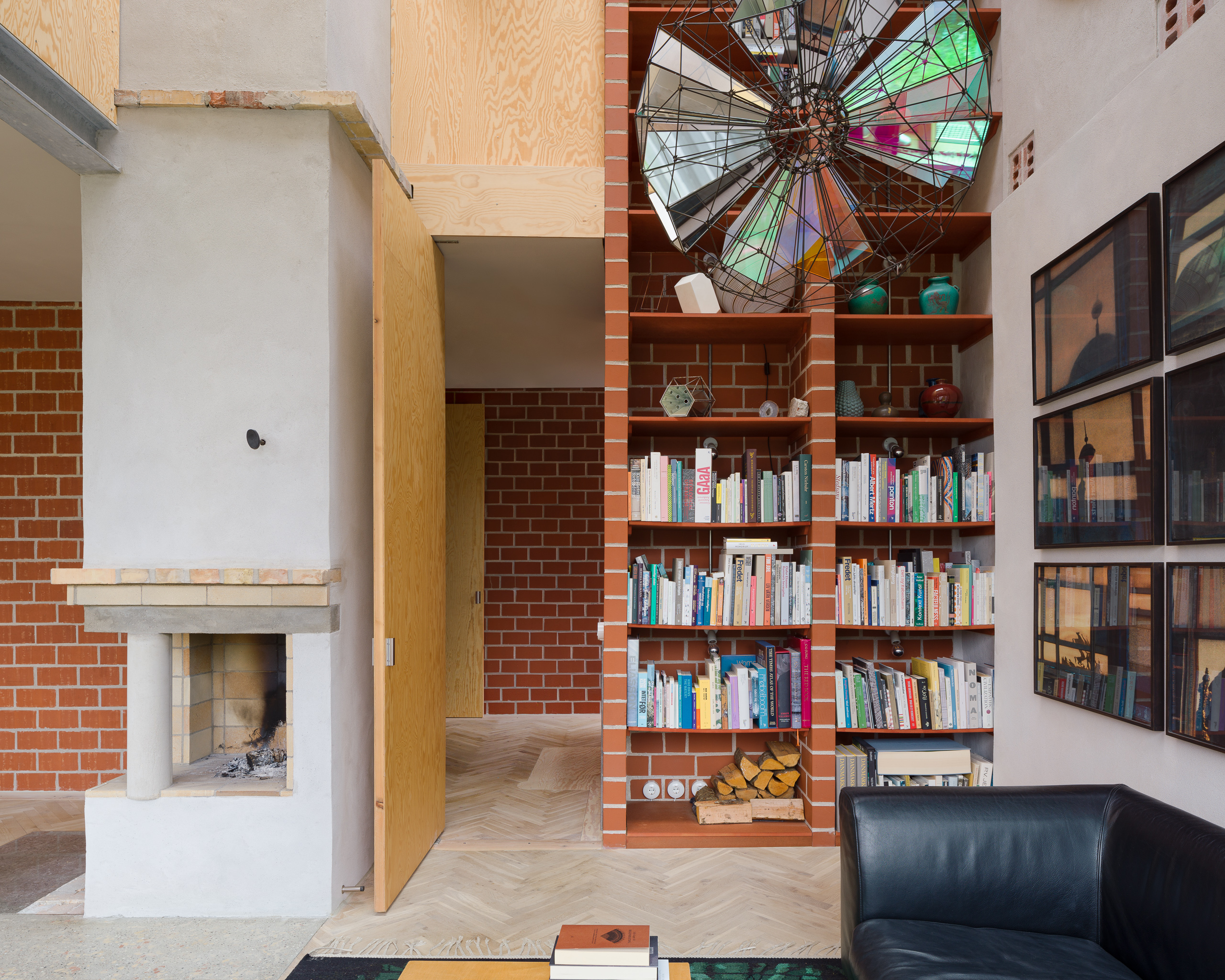 Interior shot of a brick bookcase and a white fire place in art historian and curator Marianne Krogh's living room.