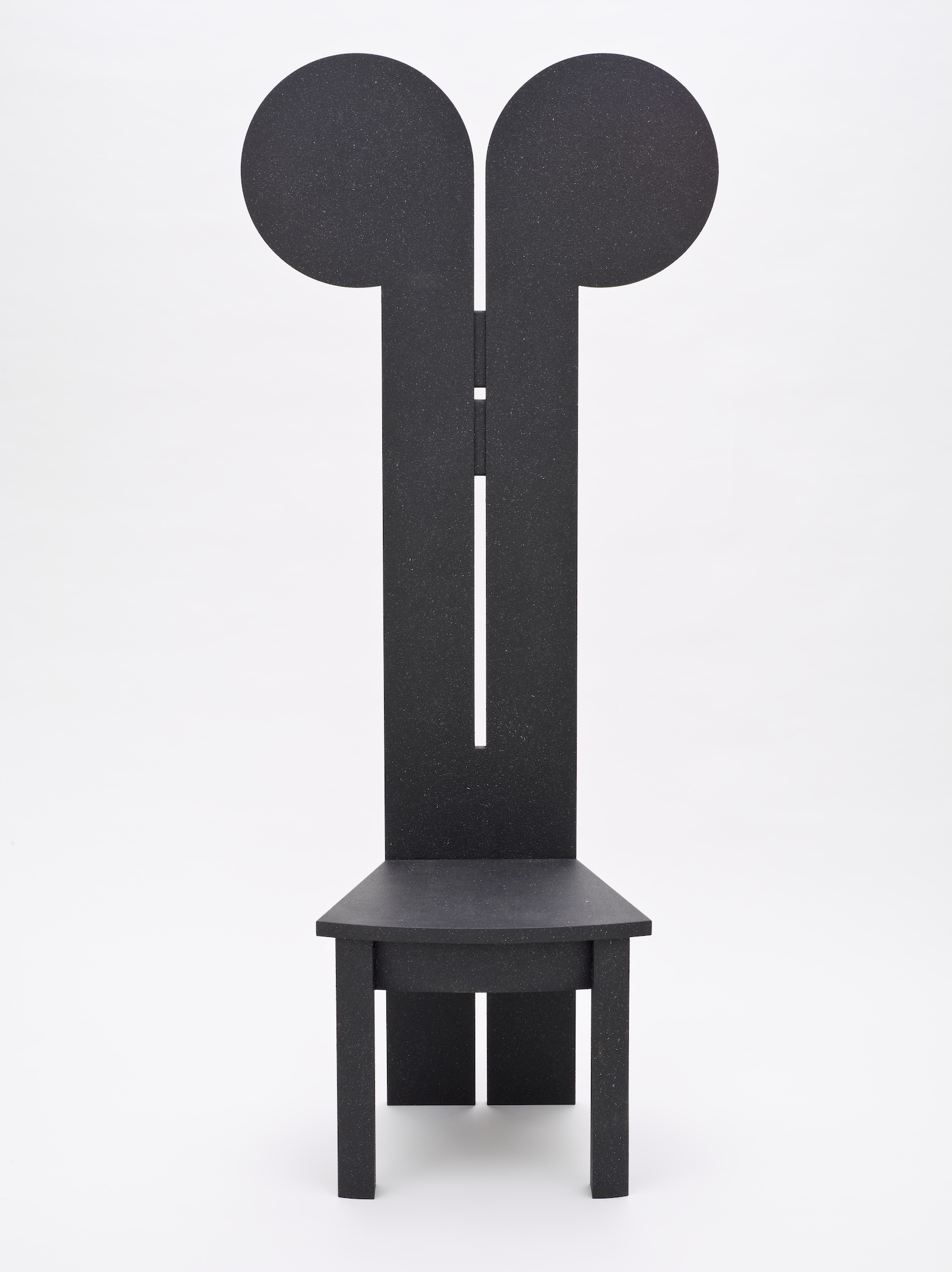 Black chair with very long back, the top of which is shaped like Mickey Mouse ears