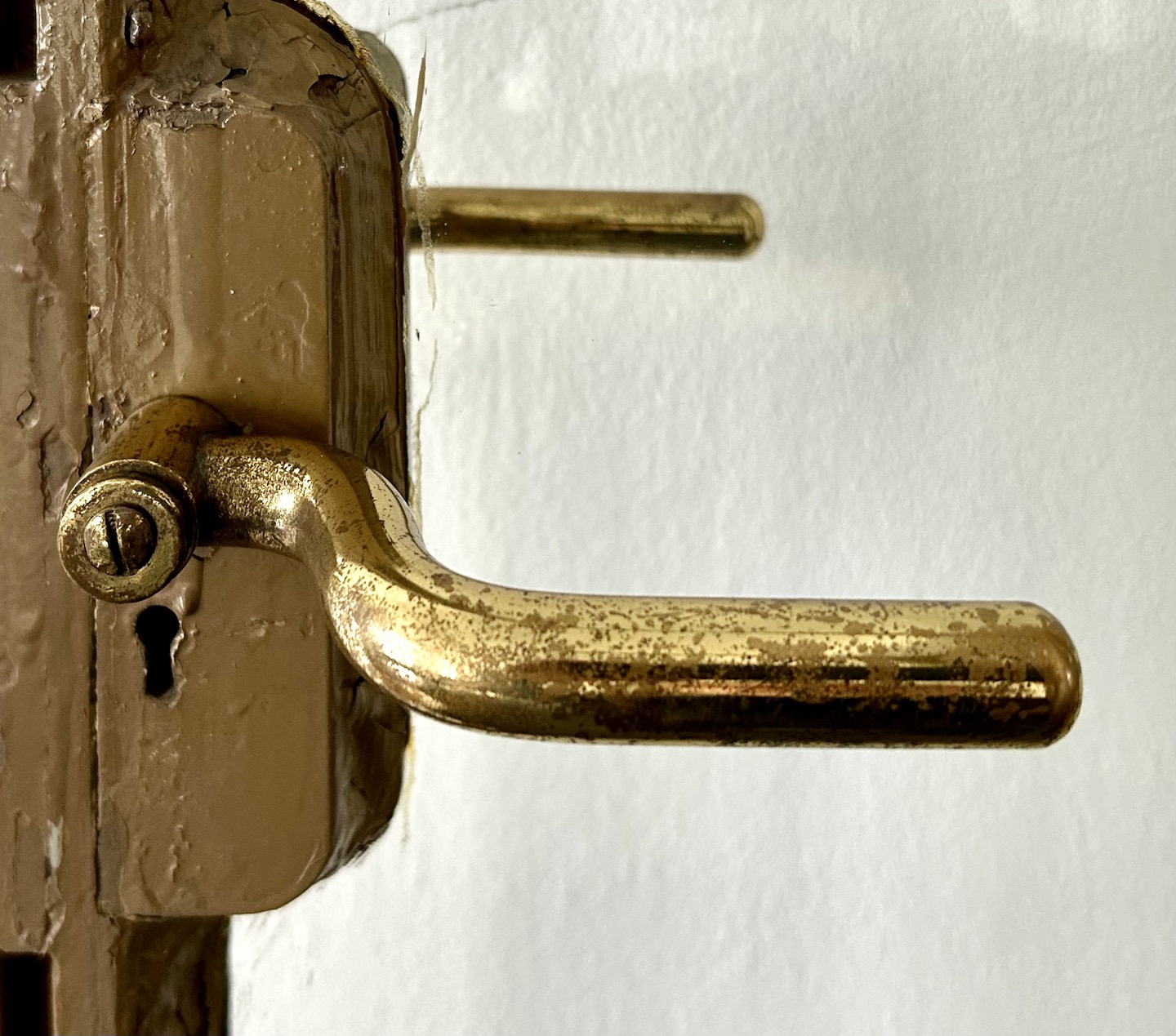 Close up of weathered door handles on glass door, showing the handles on either side of the glass pointing in different directions.