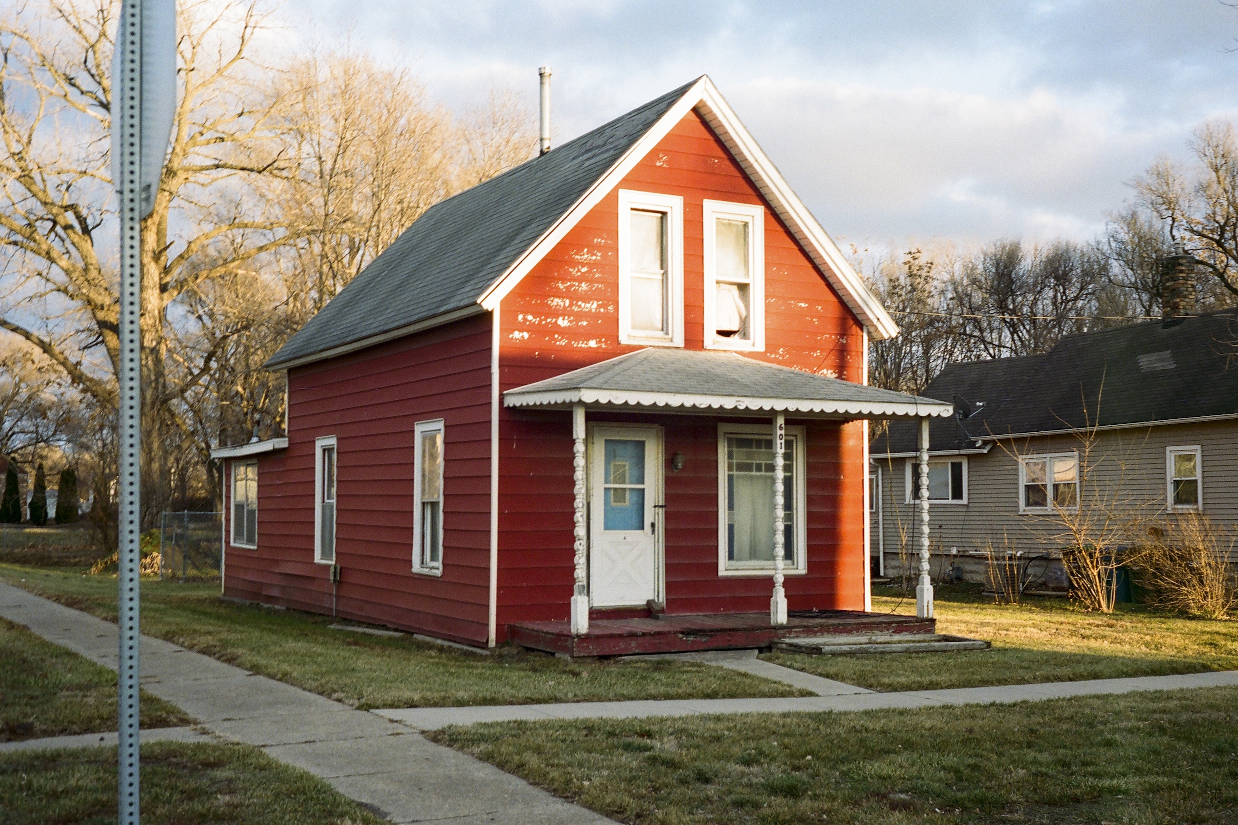 Bright red house on a corner partially covered by sun